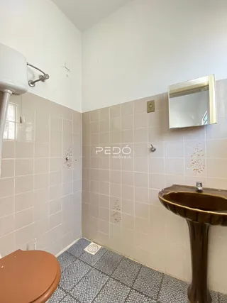 Parede de banheiro com revestimento cerâmico e pia de bronze.