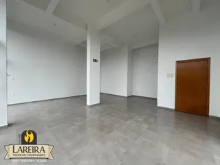 Interior de um espaço amplo com paredes brancas e piso de concreto.