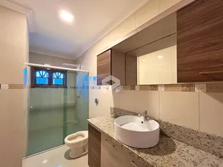 Banheiro com box de vidro e pia de apoio em Lajeado.