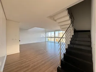 Sala de estar ampla com piso de madeira e escadaria.