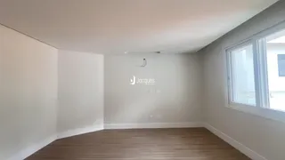Uma sala de estar com paredes brancas e piso de madeira clara.