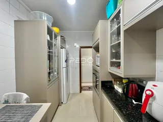 Cozinha com armários brancos e piso claro.