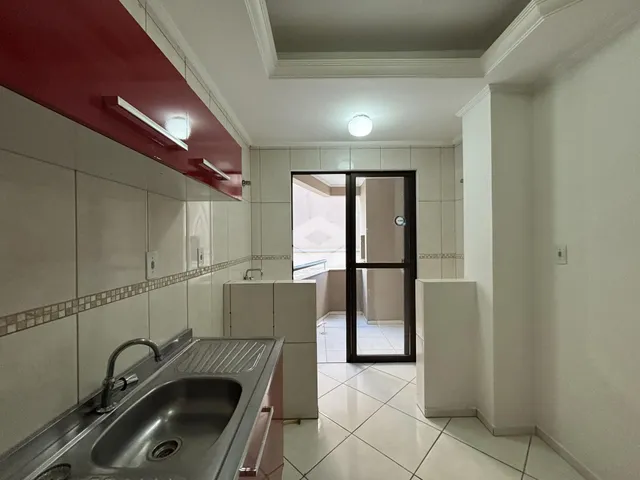 Vista da cozinha com armários brancos e revestimento cerâmico.