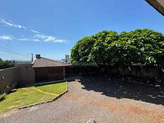 Vista externa da propriedade mostrando vegetação densa e uma área de acesso pavimentada.