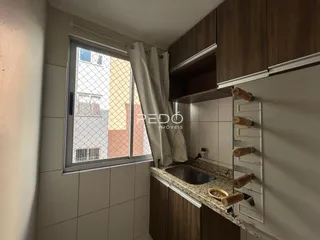 Vista interna de uma cozinha com armários de madeira e janela.