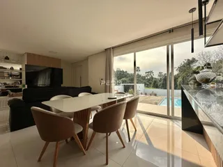 Sala de jantar e estar com vista para o jardim e piscina.