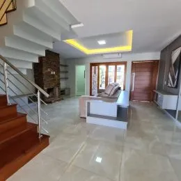 Foto de um corredor interno com escadaria e piso de cerâmica claro.