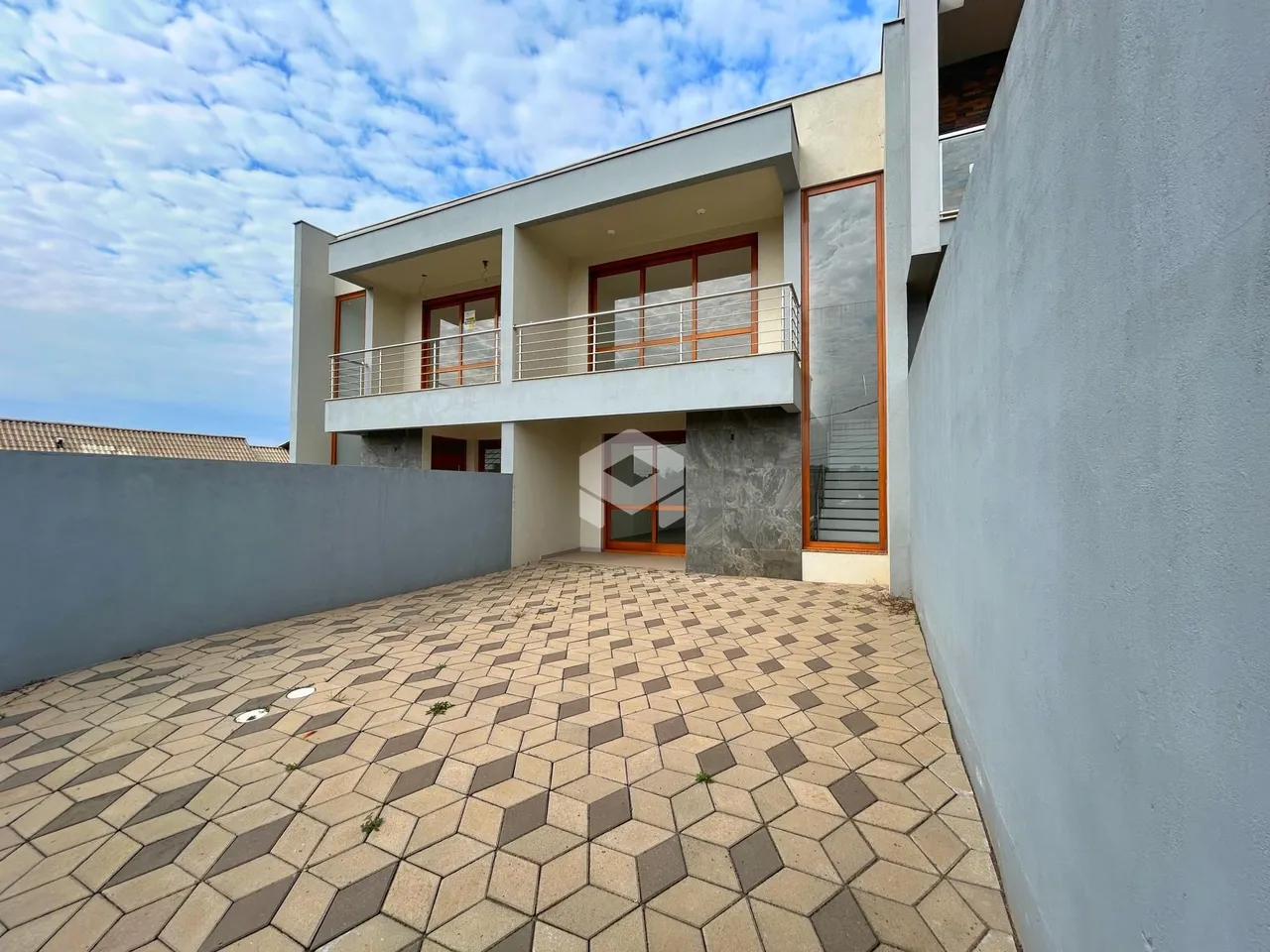 Fachada de uma residência moderna em Lajeado, Brasil, com terraço pavimentado.