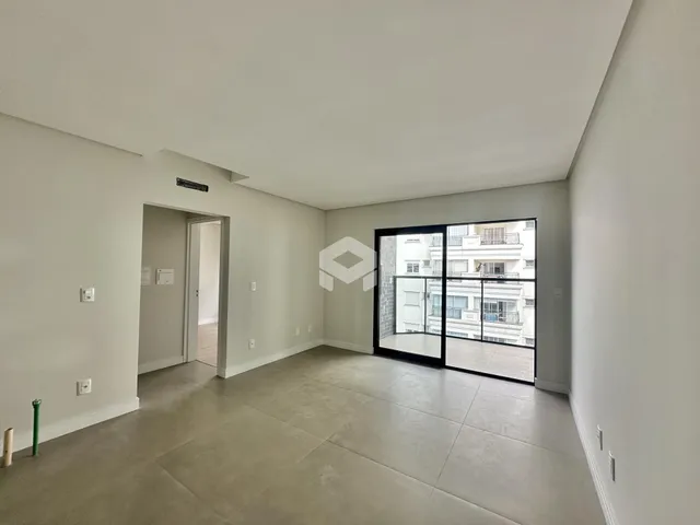 Interior de uma sala com piso claro e porta de vidro.