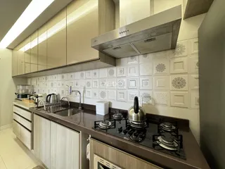Cozinha moderna com armários claros e revestimento de azulejos brancos.