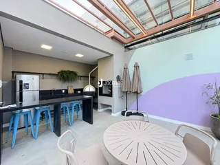 Vista de uma área de cozinha e jantar moderna com iluminação natural.