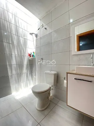 Foto de um banheiro com paredes brancas e piso de cerâmica.