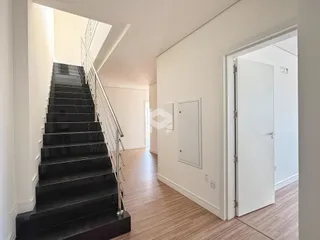 Hall de entrada com escadaria e piso de madeira.