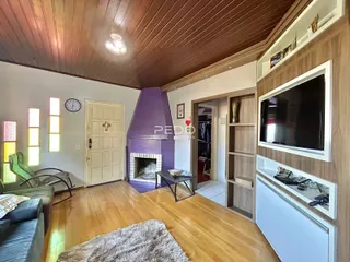 Sala de estar com piso de madeira e lareira em um imóvel no Brasil.