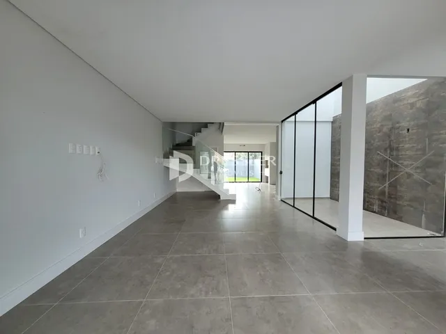 Ambiente interno moderno com piso de cerâmica e grandes portas de vidro.