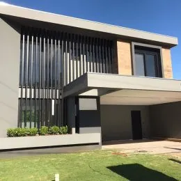 Fachada moderna de uma residência com revestimento escuro e área coberta.