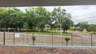 Uma cerca de ferro delimita a propriedade com árvores ao fundo.