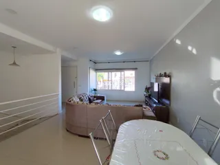 Sala de estar com sofá e mesa de jantar em ambiente claro.