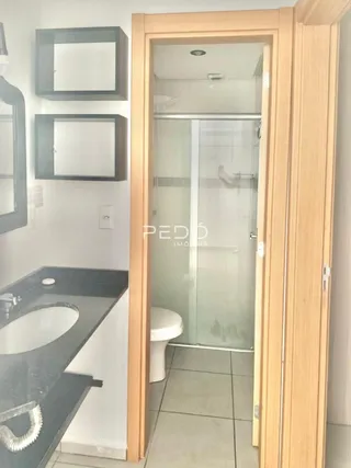 Vista interna de um banheiro com box de vidro e vaso sanitário.