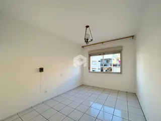 Uma sala de estar com paredes brancas e piso de cerâmica.