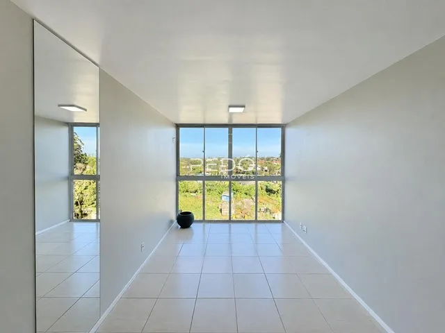 Hall de entrada com piso claro e grande janela de vista para a natureza.