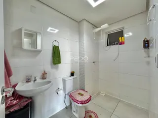 Foto interna de um banheiro com azulejos brancos e louças sanitárias brancas.