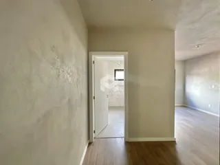 Hall de uma residência com piso de madeira clara e paredes brancas.
