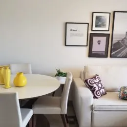 Foto de uma sala de estar com sofá branco e quadros na parede.