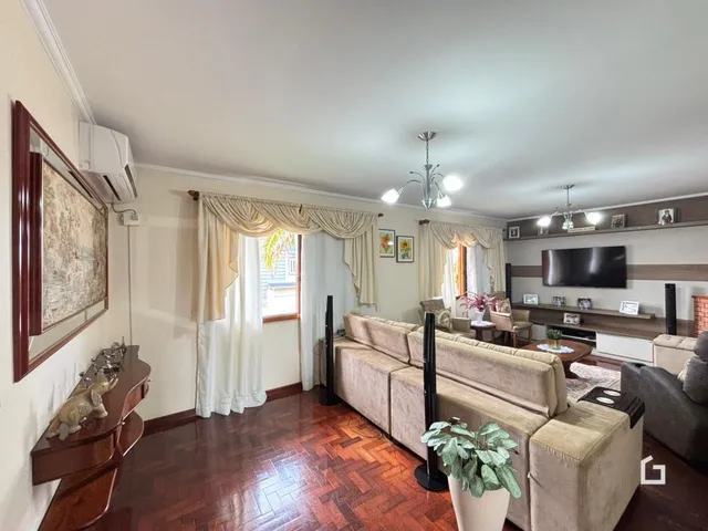 Sala de estar com piso de madeira e cortinas claras.
