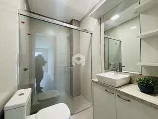Foto de um banheiro com box de vidro e vaso sanitário.