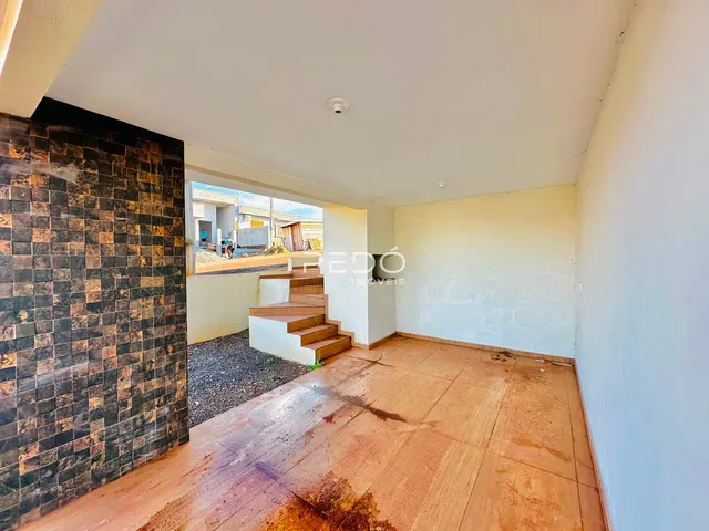 Ambiente interno com piso de madeira e parede de tijolos escuros em uma residência.