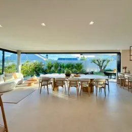 Sala de estar ampla com piso claro e grandes janelas que dão vista para o exterior.