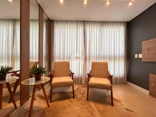 Sala de estar com cortinas claras e cadeiras de madeira.