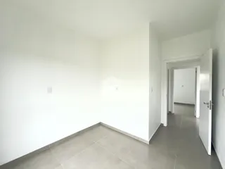 Corredor interno com piso de cerâmica claro e paredes brancas.
