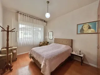 Quarto com cama e janela bem iluminada.