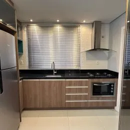 Foto de uma cozinha com armários de madeira e bancada escura.