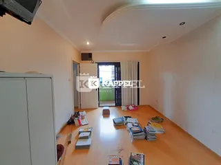 Uma sala de estar com piso de madeira e um armário branco.