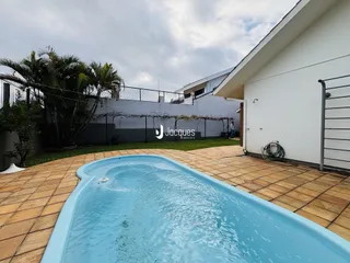 Piscina externa com deck de tijolos no quintal.