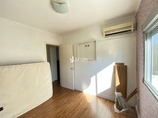 Quarto interno com piso de madeira e parede branca.