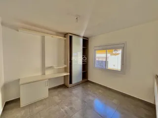 Sala de estar com paredes brancas e piso de cerâmica.