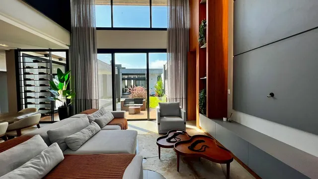 Sala de estar com sofá grande e portas de vidro que oferecem vista para o exterior.