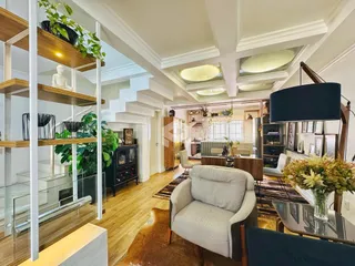 Interior de uma sala de estar com pé direito alto e estantes de madeira.