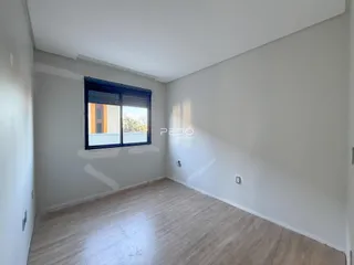 Ambiente interno de uma sala com piso de madeira e parede branca.