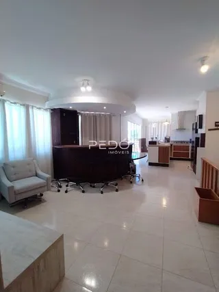 Sala de estar com janelas cobertas por cortinas claras.