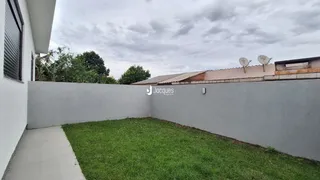 Vista externa da propriedade com muro branco e gramado.