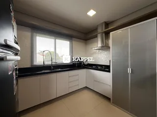 Cozinha moderna com armários brancos, bancada preta e eletrodomésticos em um ambiente bem iluminado.