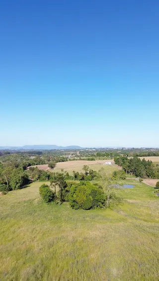 Vista aérea de uma paisagem rural com campos verdes e vegetação.
