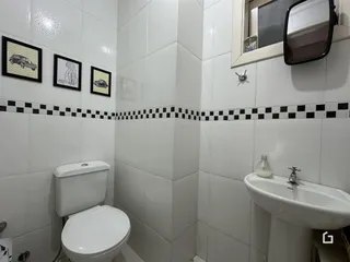 Foto do interior de um banheiro com revestimento de azulejos brancos e pretos.