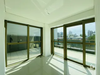 Vista interna de uma sala com grandes janelas de vidro.