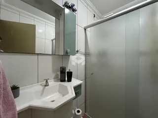 Interior de um banheiro com pia e box de vidro.